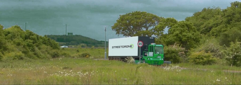 Green autonomous truck with StreetDrone logo drives on a 20mph road